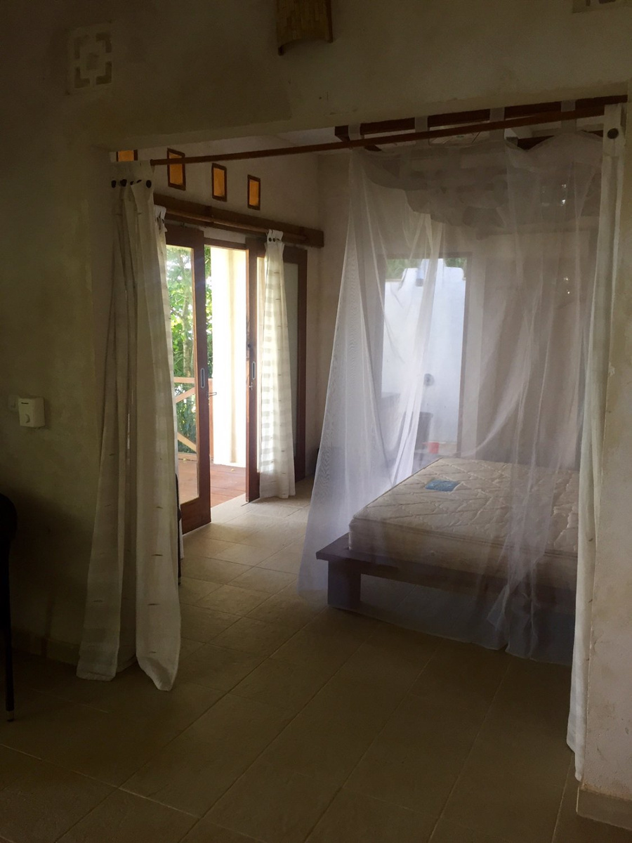 The hillside villa bedroom, with a mosquito net over the bed and doors opening onto the terrace.
