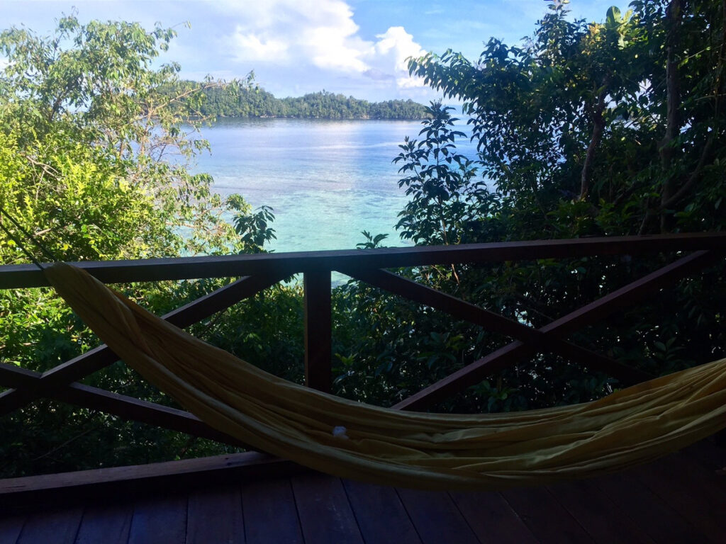 A hammock on the hillside villa’s shaded wooden terrace overlooking the sea.