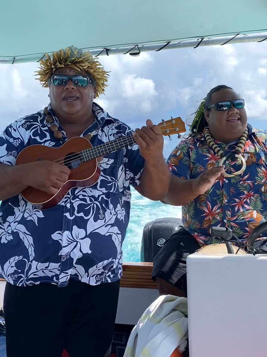 Our guide playing a ukulele beside another crew member aboard the excursion boat on the Bora Bora lagoon