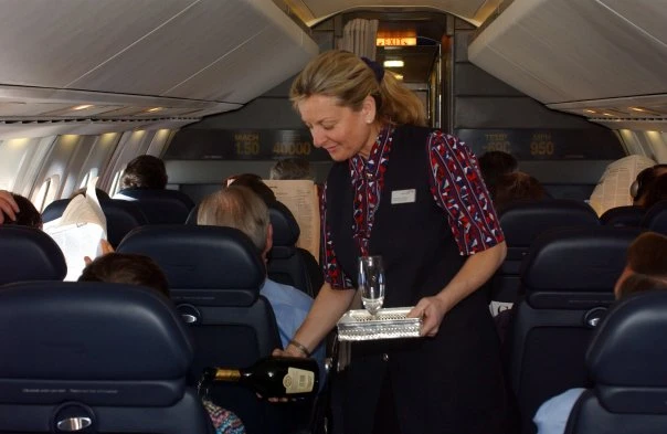 A British Airways cabin crew member pours champagne for passengers in the narrow Concorde cabin.