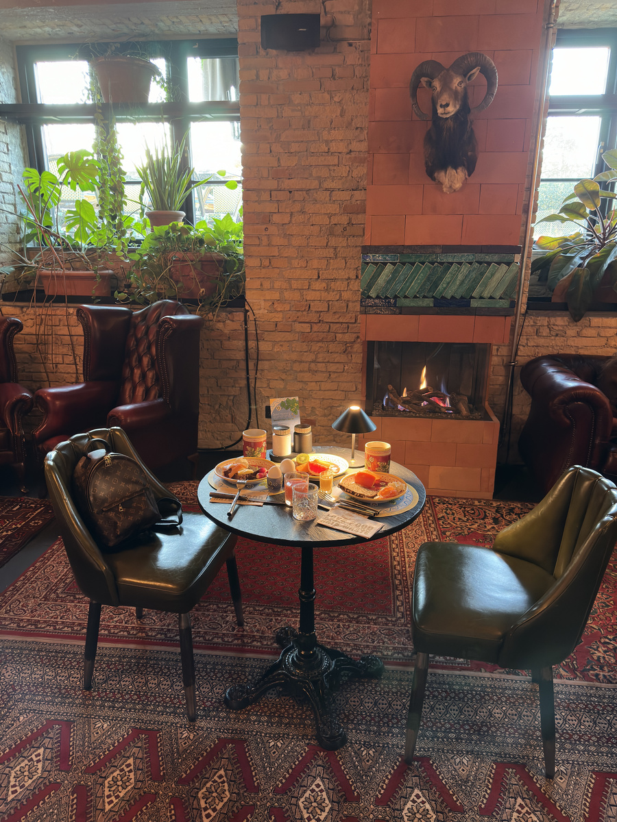 Breakfast laid on a round table beside the fireplace at Bryggen Guldsmeden