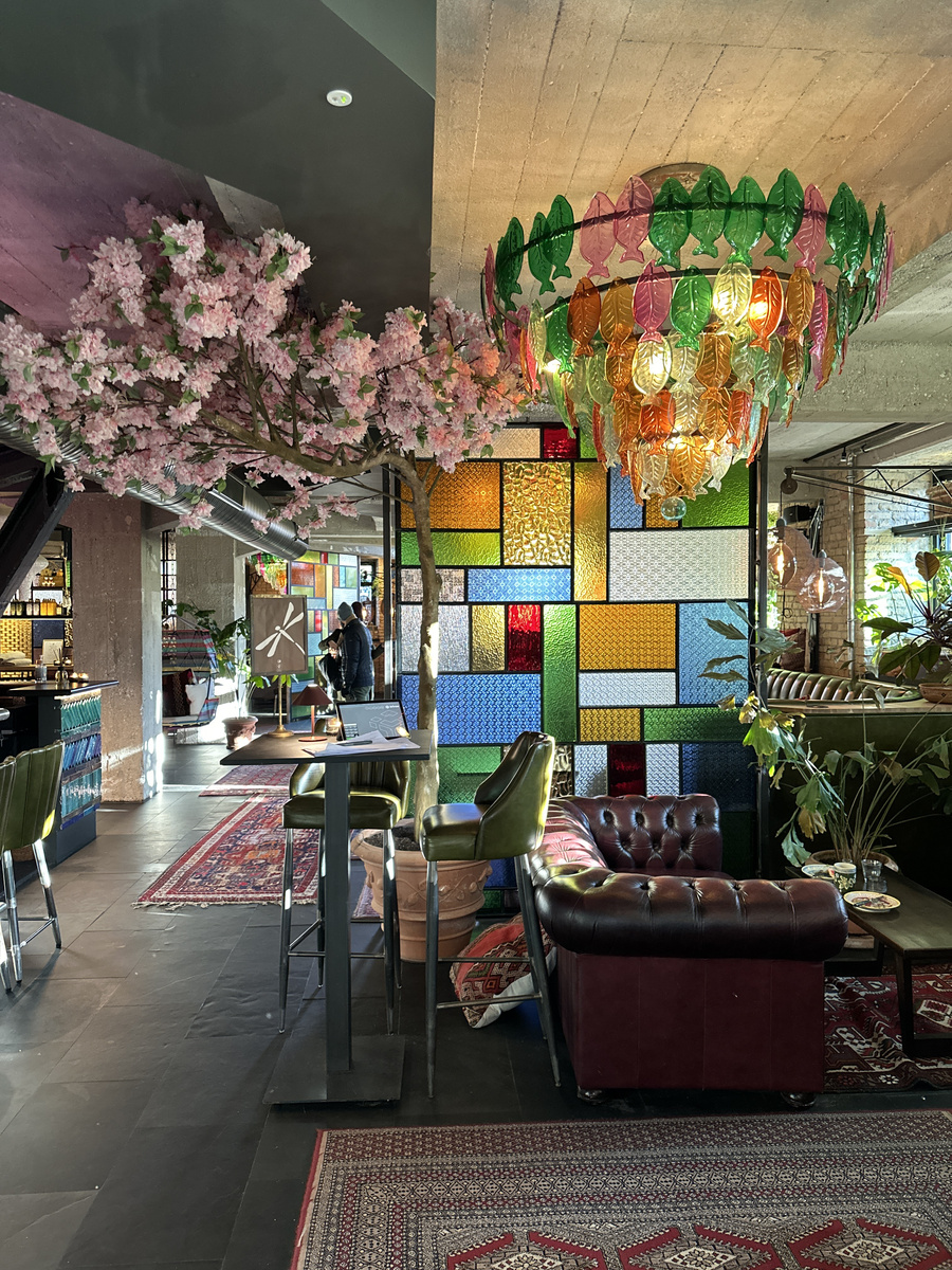 A coloured glass fish chandelier above leather seating in the hotel lounge