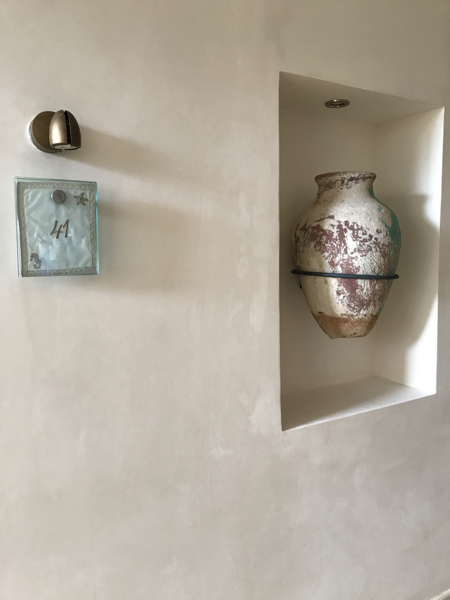 Ceramic vessel in a wall niche beside a guest-room door