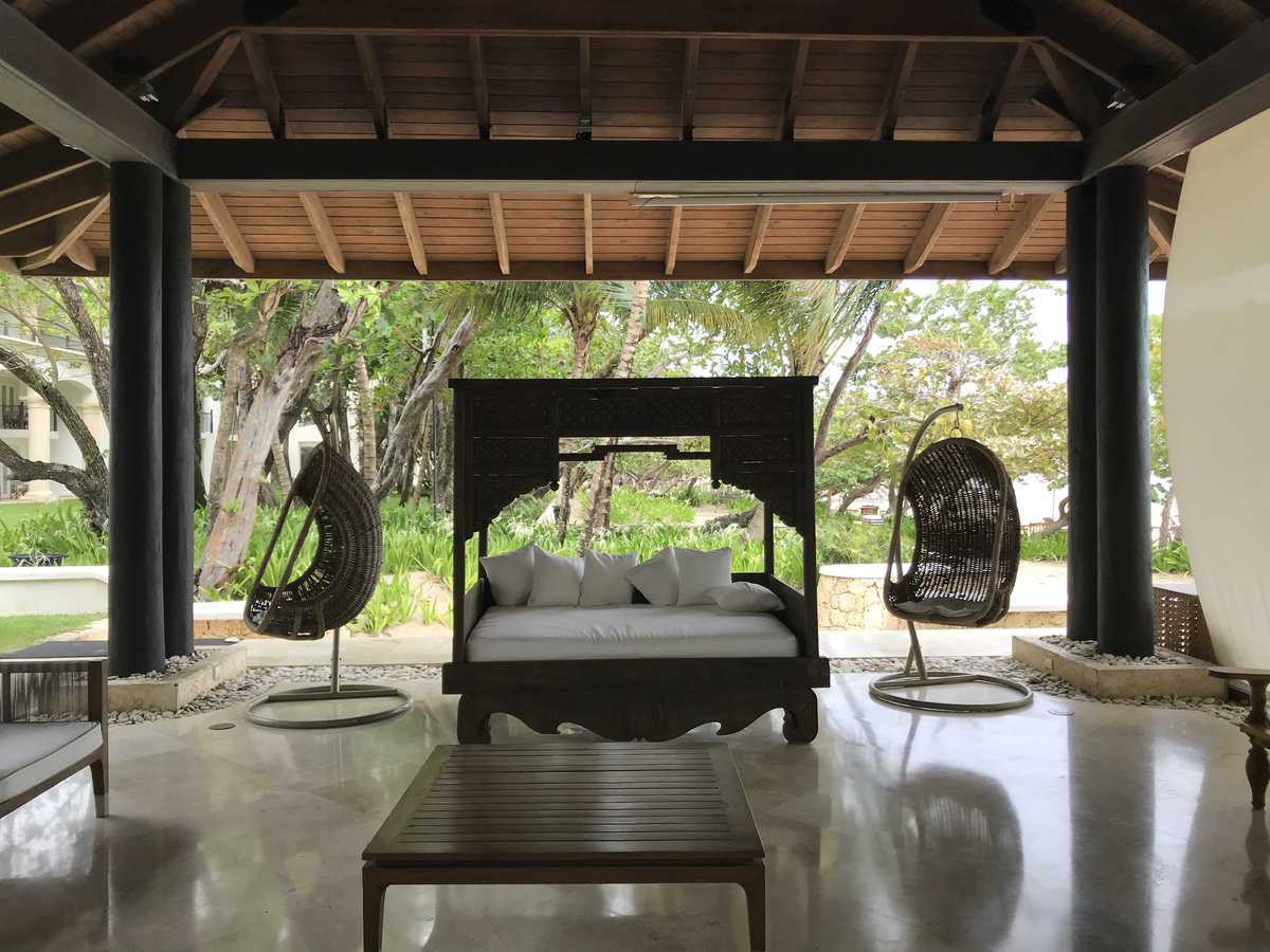 Open-sided pavilion with a carved daybed and hanging chairs at Casa Colonial