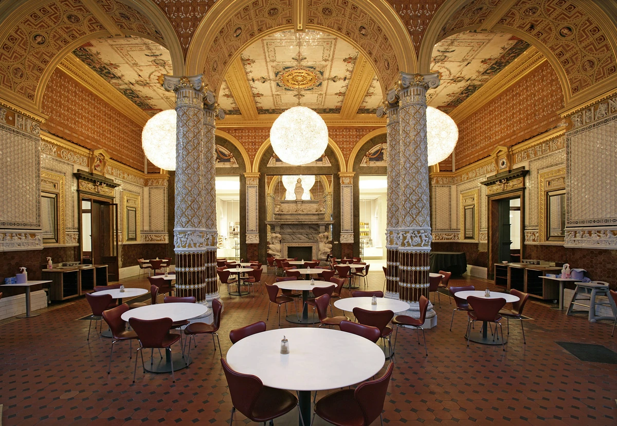 Tables and chairs beneath globe lights, decorated columns and a painted ceiling in the V&A’s Gamble Room.