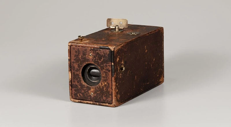Original Kodak box camera with a circular lens opening and worn leather covering.
