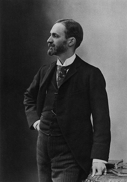 George Eastman in profile, wearing a dark suit and patterned tie.