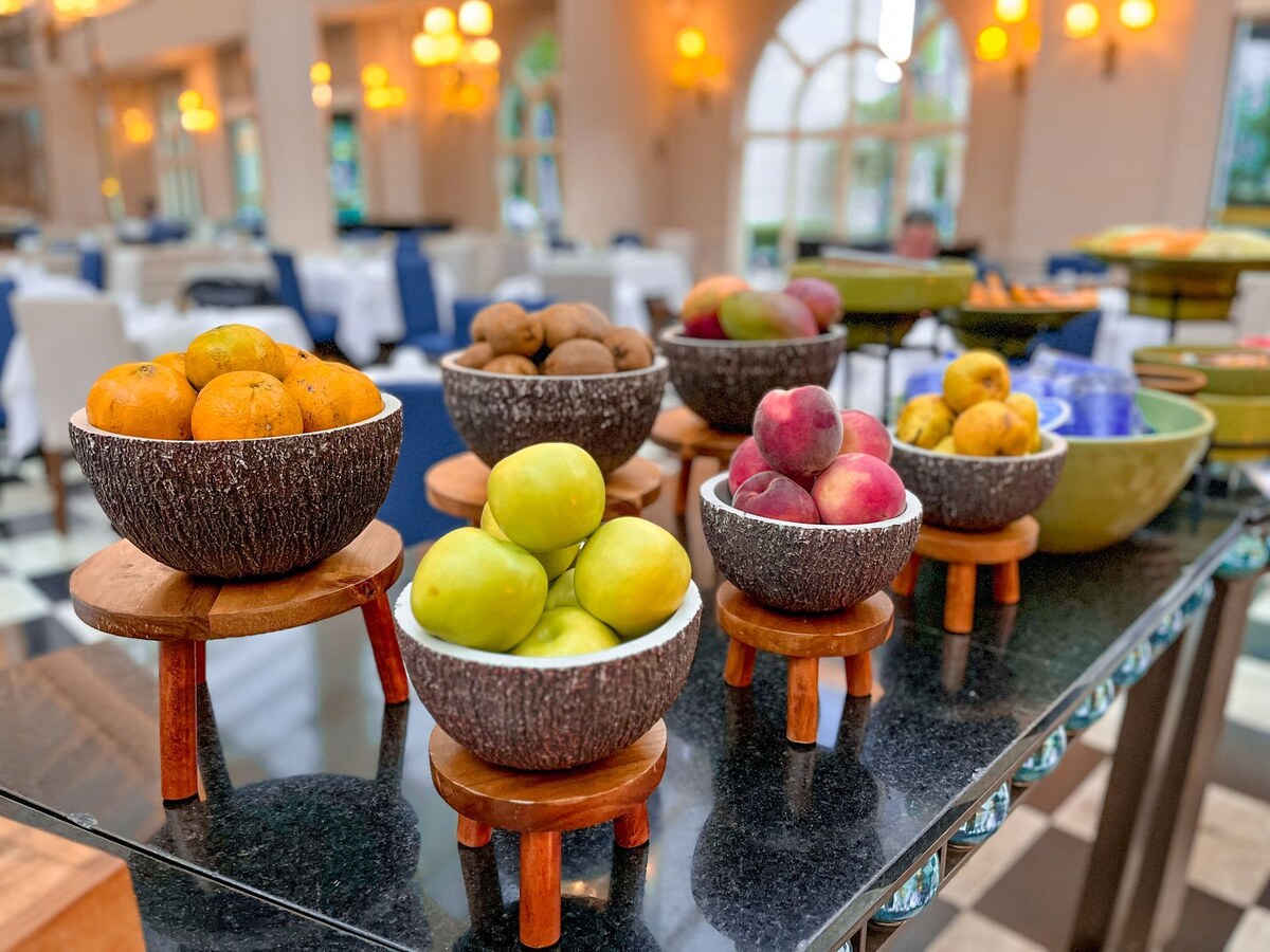 Oranges, apples, peaches and kiwis in bark-textured bowls on the breakfast buffet.