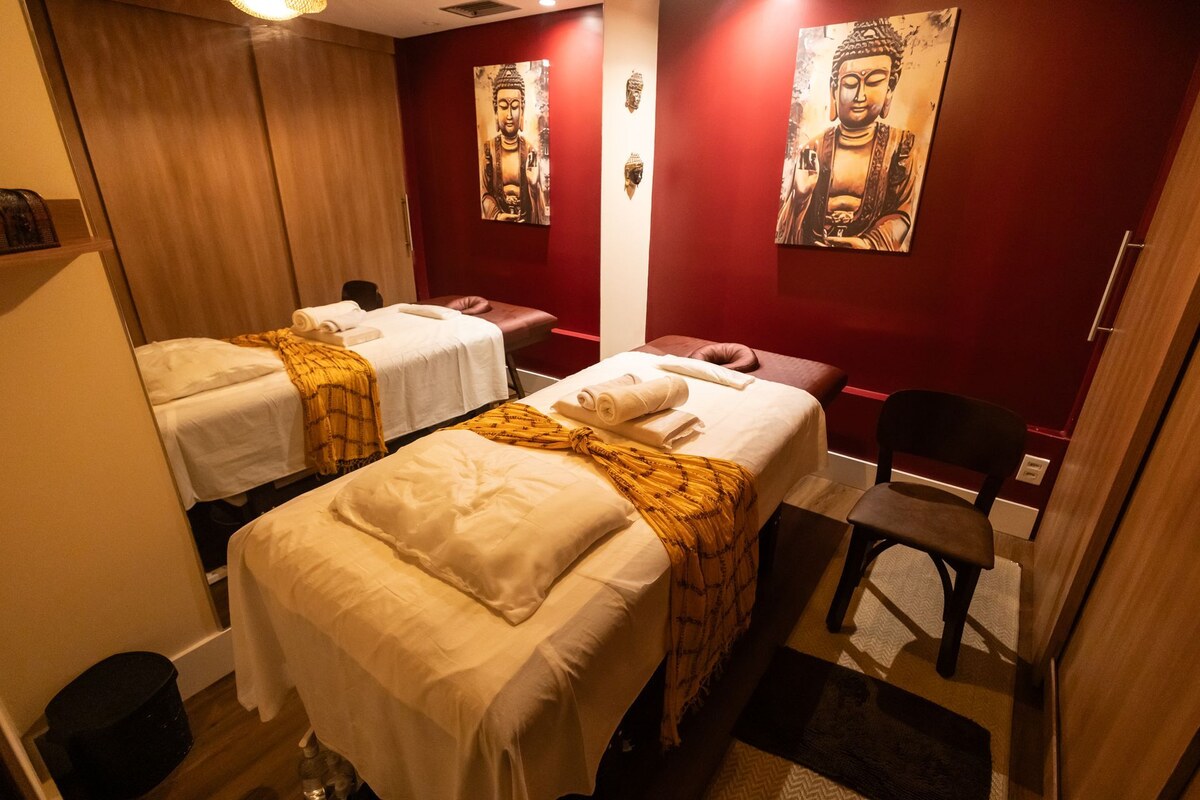 Two massage tables in a Buddha Spa treatment room with red walls and Buddha prints.