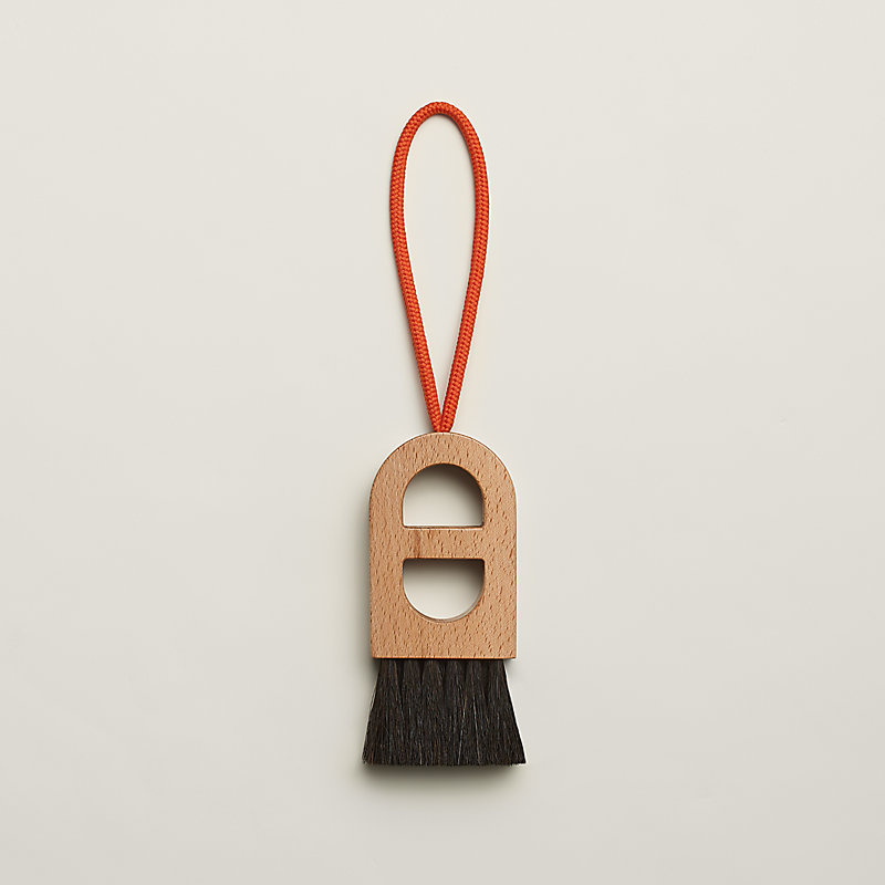 Wooden Hermès beach brush with dark horsehair bristles and an orange wrist cord.