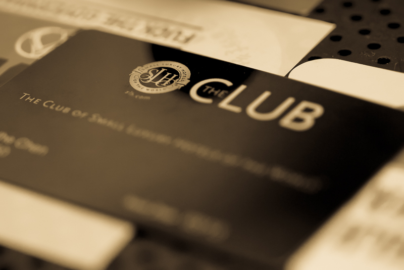 A black SLH The Club membership card lies at an angle across its printed welcome material.