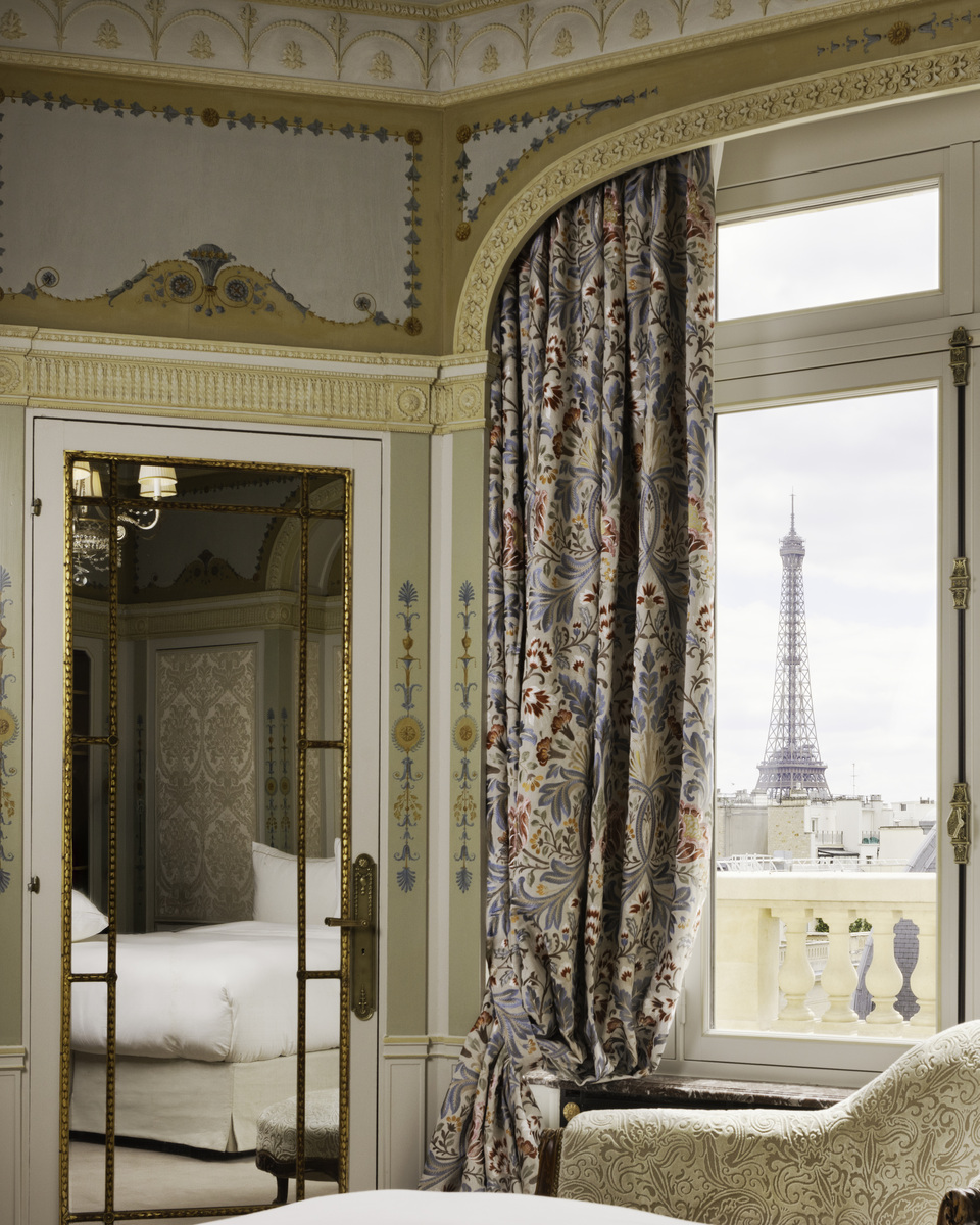 The Eiffel Tower framed by a window beside a gilded mirror in a Hôtel Raphael suite.