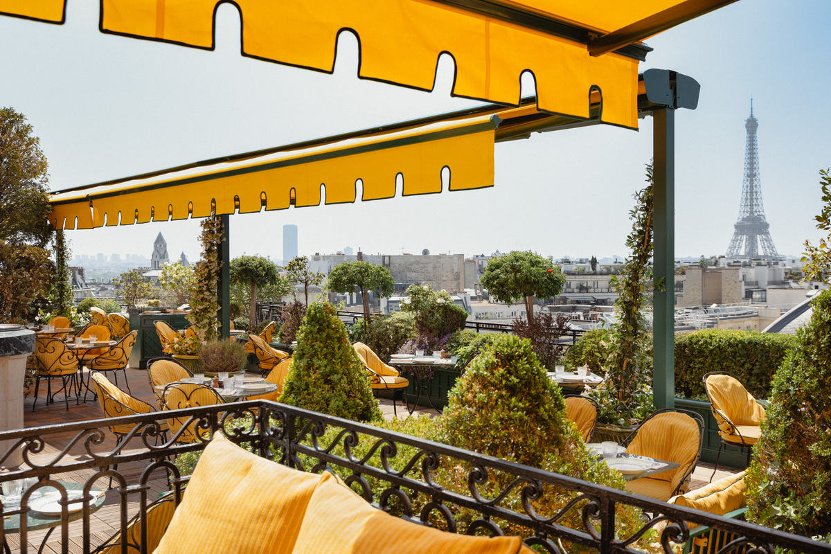 Yellow awnings and garden seating on the rooftop of Hôtel Raphael, with the Eiffel Tower beyond.