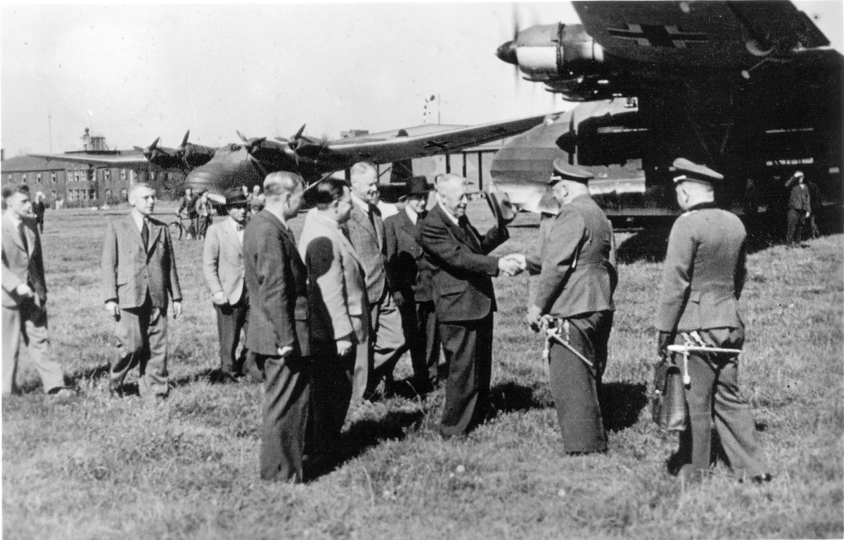 Hugo Eckener in civilian clothes shaking hands with a uniformed official in front of Messerschmitt Me 323 transport aircraft in 1942.