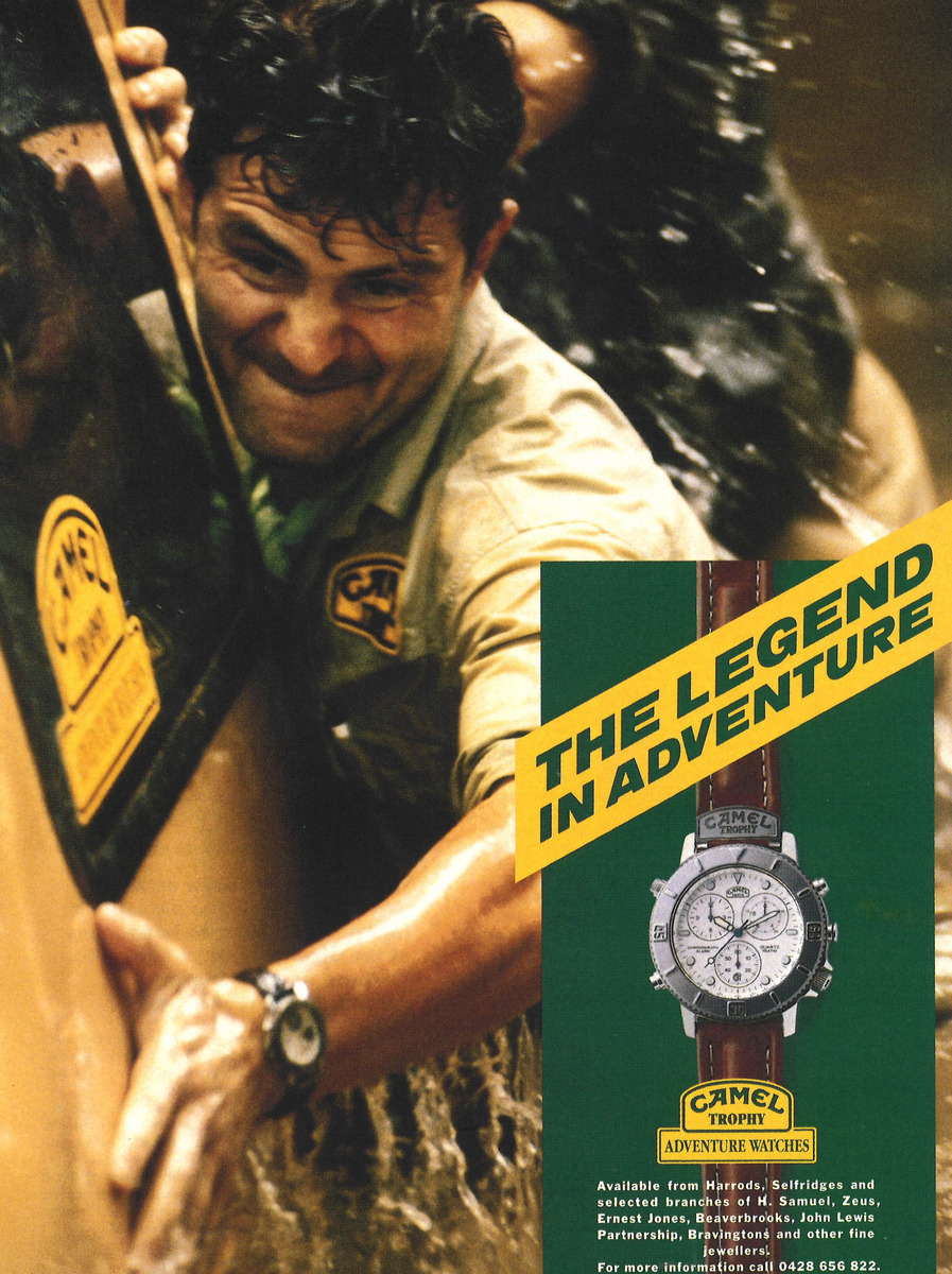 Colour Camel Trophy Adventure Watches advertisement showing a man beside a vehicle and a large wristwatch below a diagonal yellow headline.