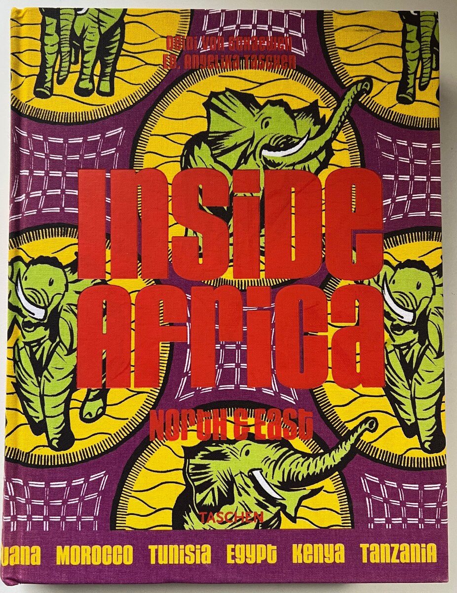 The Inside Africa North & East cloth cover by TASCHEN, printed with green elephants on yellow and purple wax-print fabric beneath red lettering.