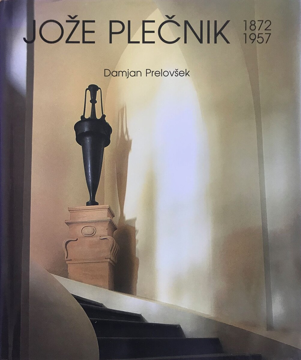The Jože Plečnik 1872–1957 jacket by Damjan Prelovšek: a dark bronze urn on a carved stone pedestal above a curving staircase, in warm light against a pale arched wall.