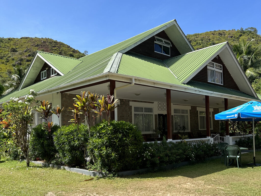 The green-roofed Le Chevalier Bay Guesthouse with its veranda and garden.