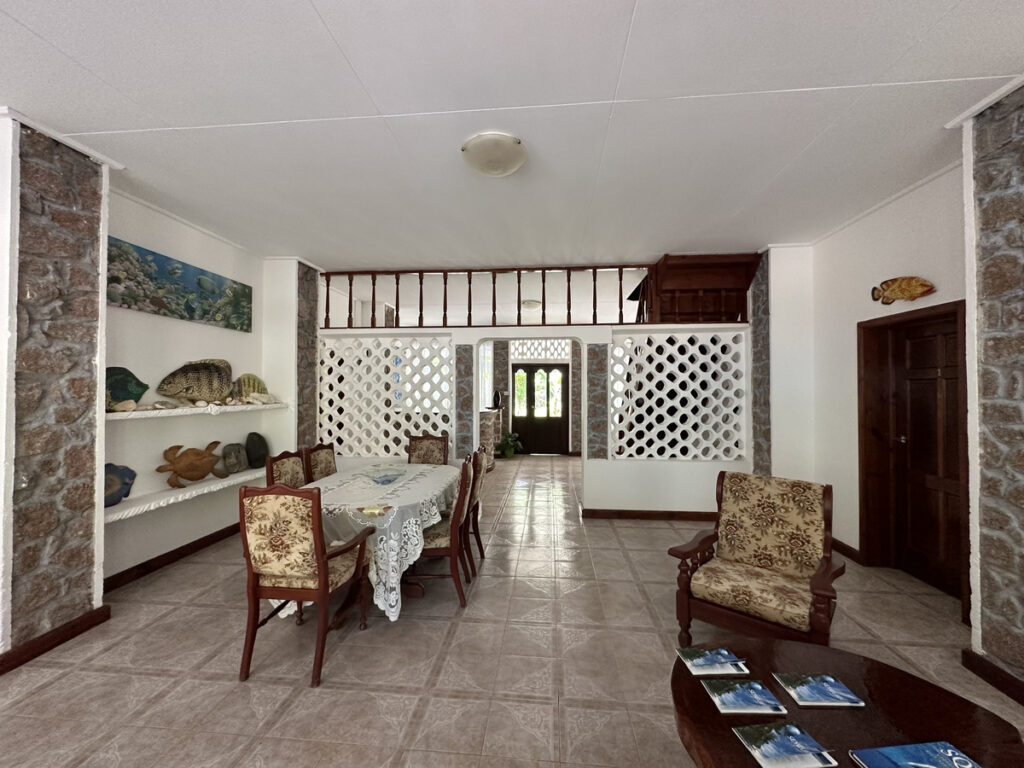 Shared interior with wooden chairs, a table and fish decorations at Le Chevalier Bay.