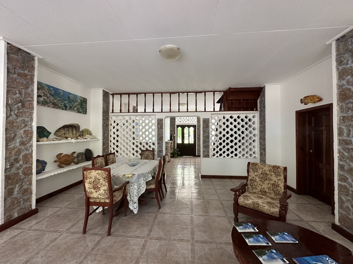 Shared interior with wooden chairs, a table and fish decorations at Le Chevalier Bay.