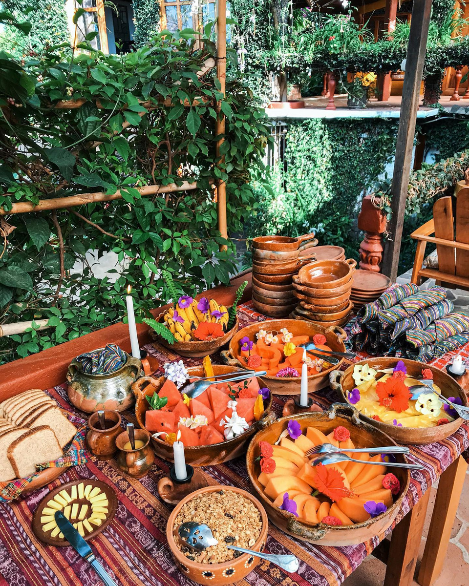 Fruit, granola, bread and pottery laid out for breakfast in the hotel garden