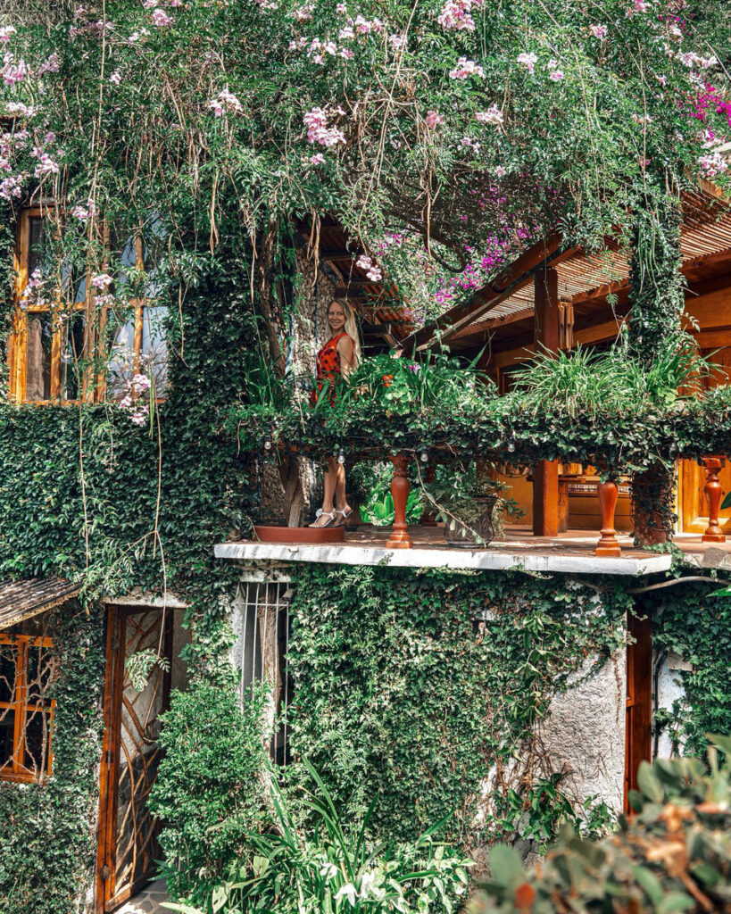 Olga standing among flowering vines on a wooden gallery at Lush Atitlán