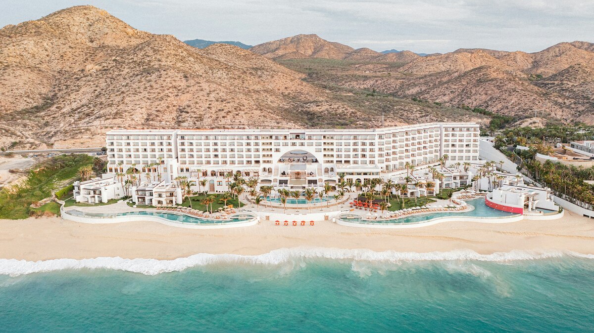 The beachfront Marquis Los Cabos resort with pools and desert hills, viewed from the sea.