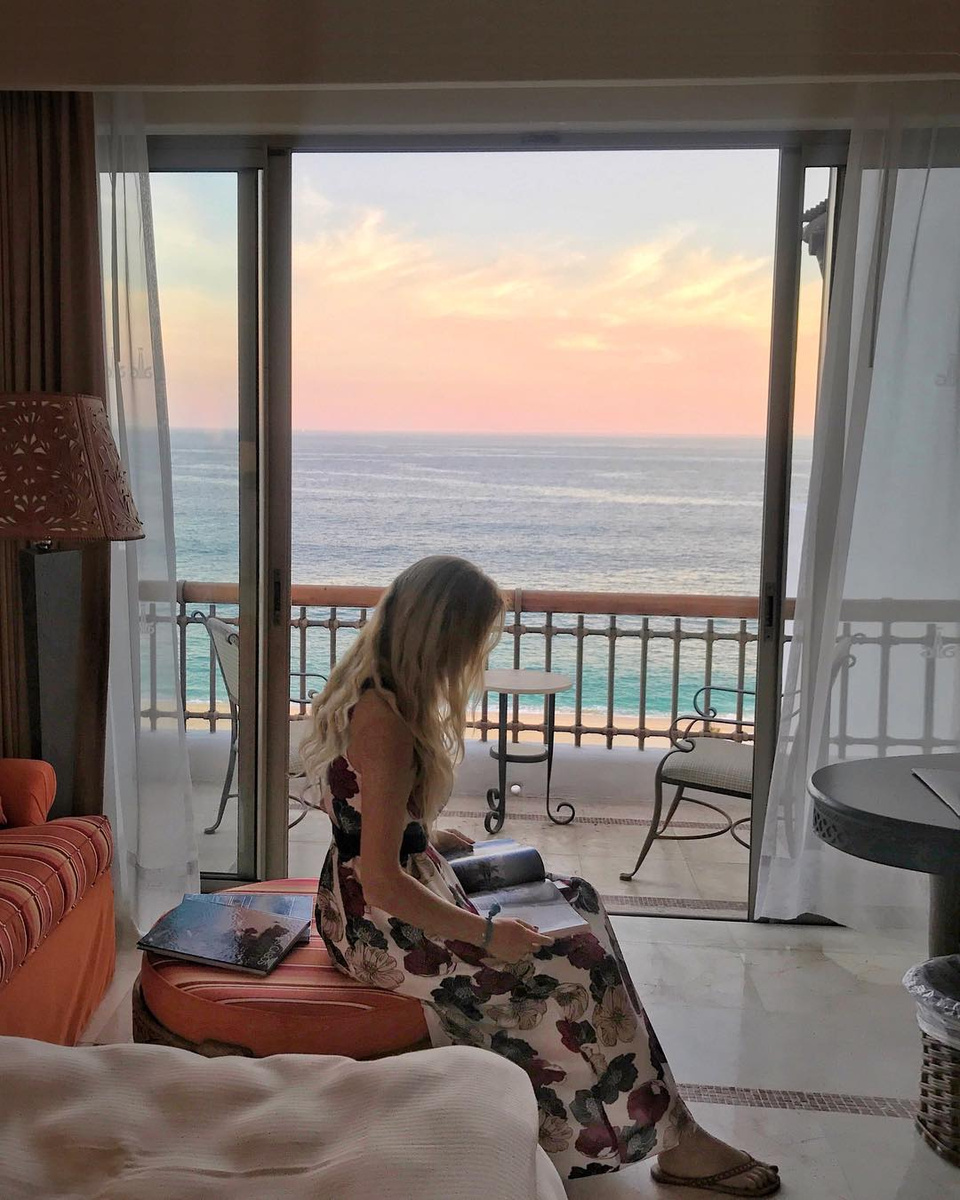 Olga reading beside the open balcony doors at Marquis Los Cabos.