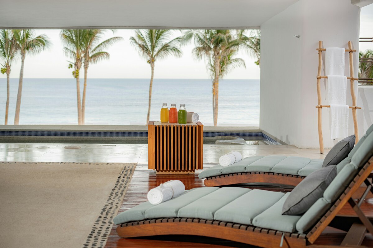 Loungers beside a spa pool overlooking palm trees and the Sea of Cortez.