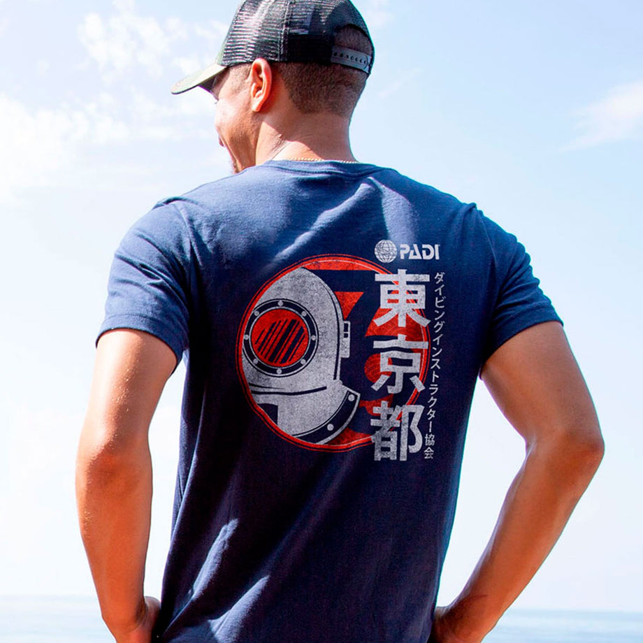 A man seen from behind wearing a navy PADI Japan T-shirt with a diving-helmet graphic and Japanese lettering.