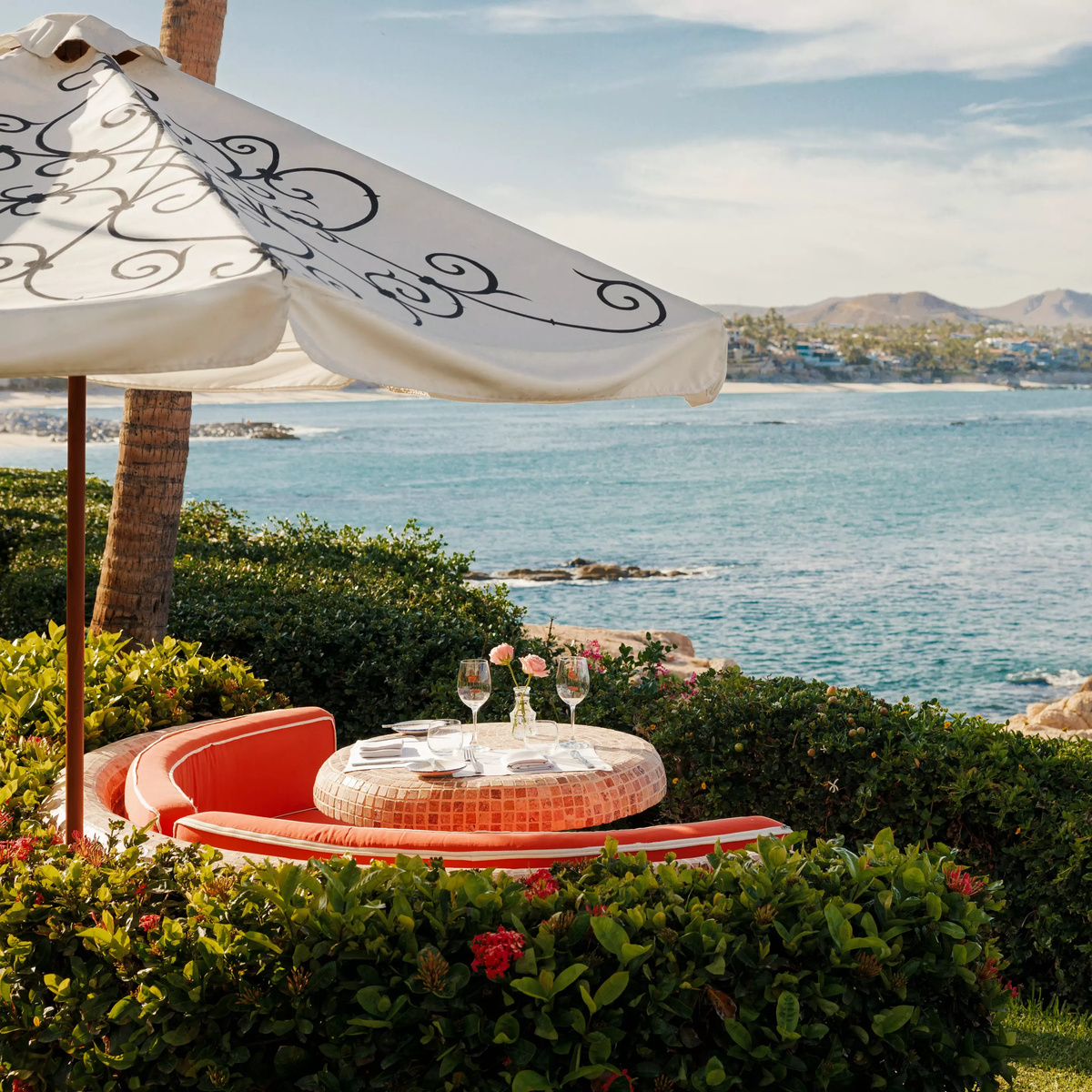 Garden dining table under a patterned umbrella above the Sea of Cortez.
