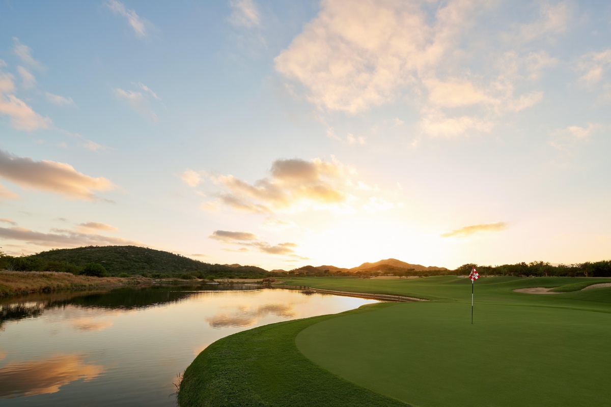 Putting green and lake at Palmilla Golf Club, with desert hills behind.