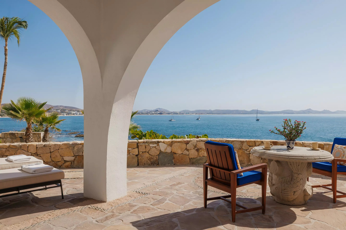 Shaded terrace with a stone table, blue chairs and a view across Palmilla Bay.