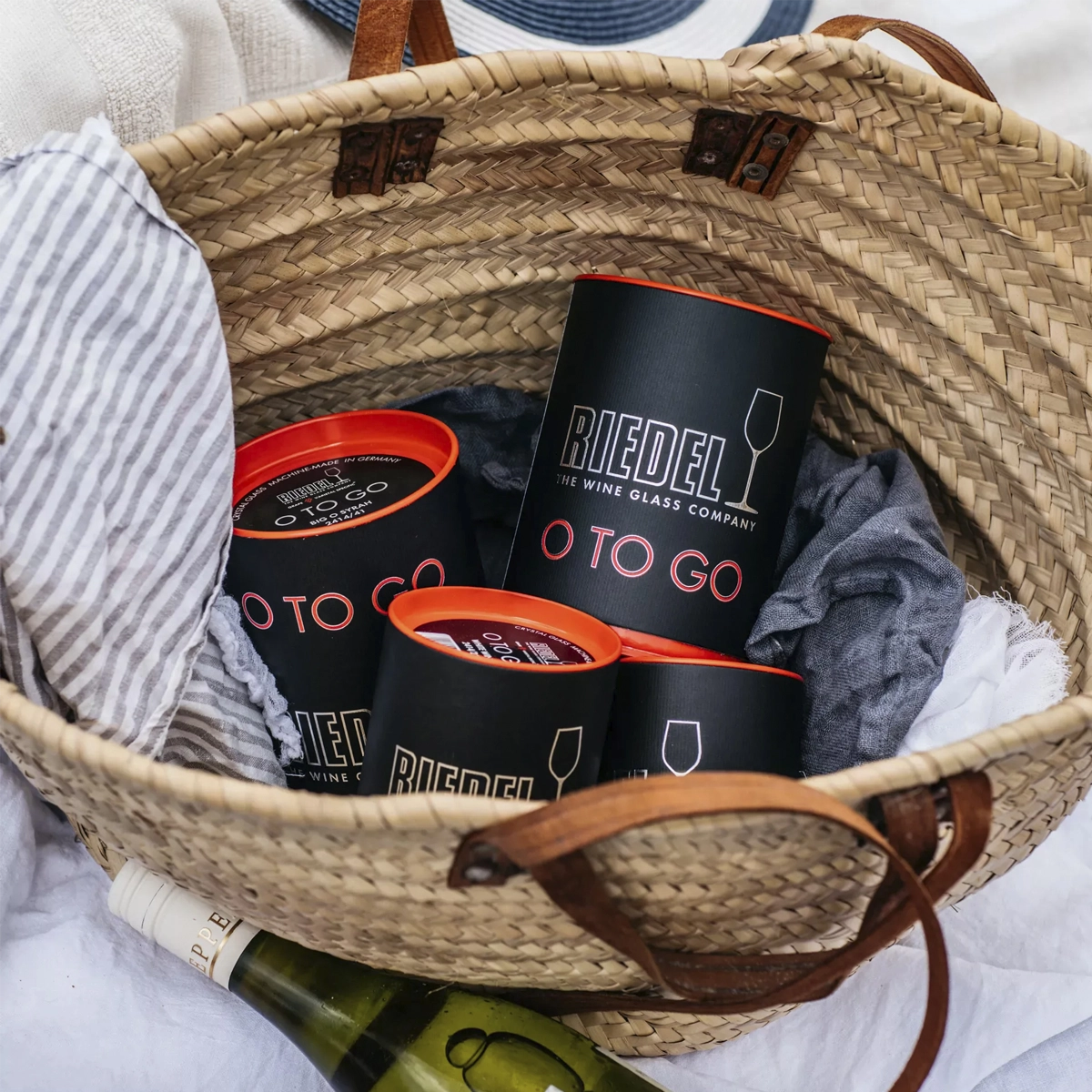 Black and red Riedel O To Go travel cases packed in a woven picnic basket.