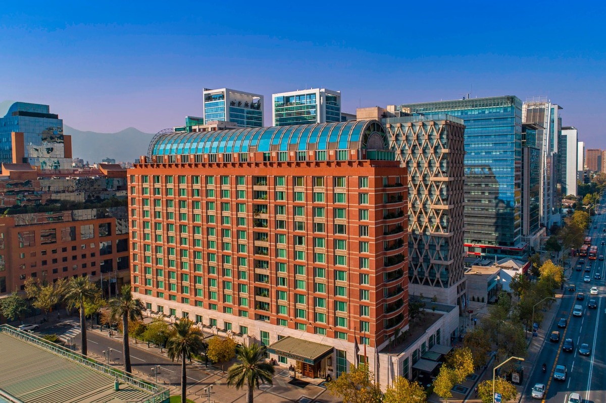 The Ritz-Carlton Santiago’s red-brick façade and arched glass rooftop among the office towers of El Golf. Photograph: The Ritz-Carlton / Marriott International.