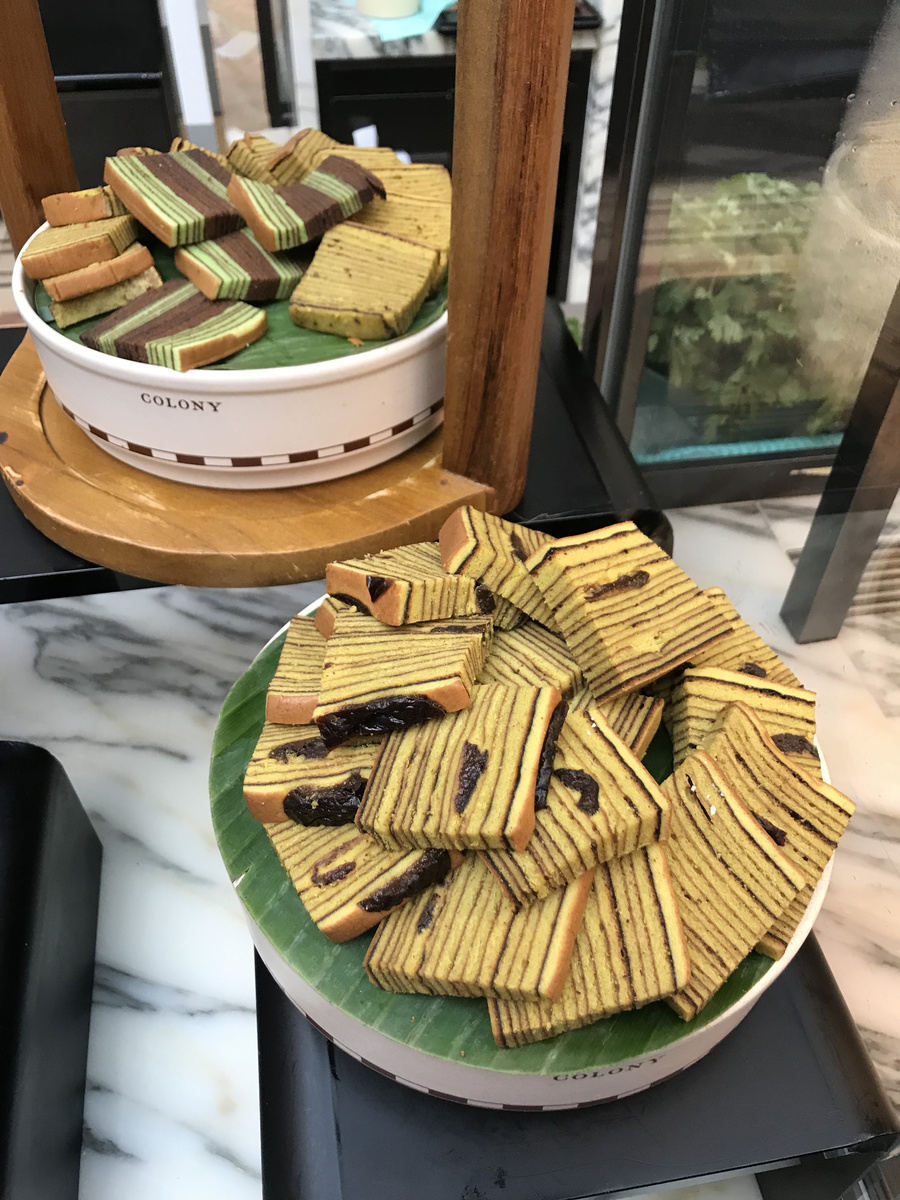 Slices of green, yellow and brown layered cakes on Colony serving stands