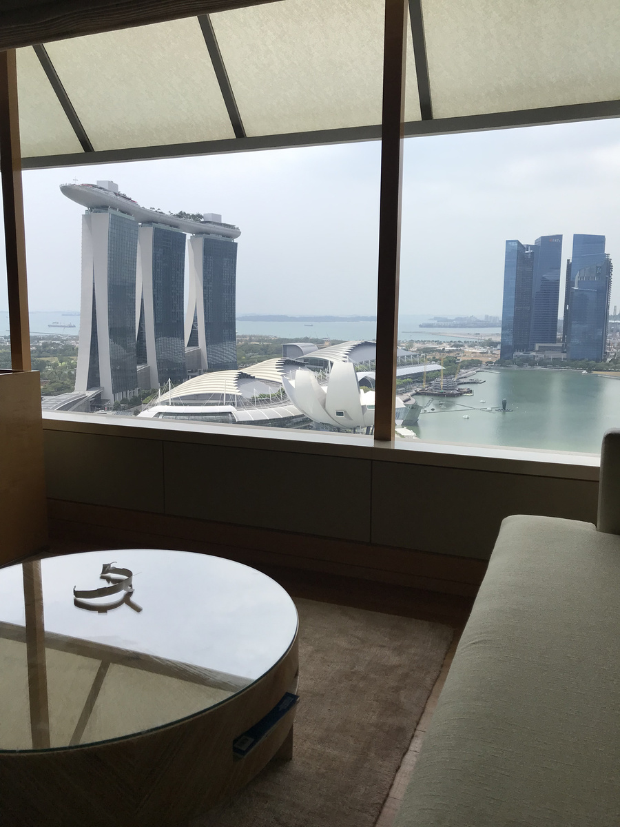 A sofa and coffee table beside a hotel window overlooking Marina Bay Sands
