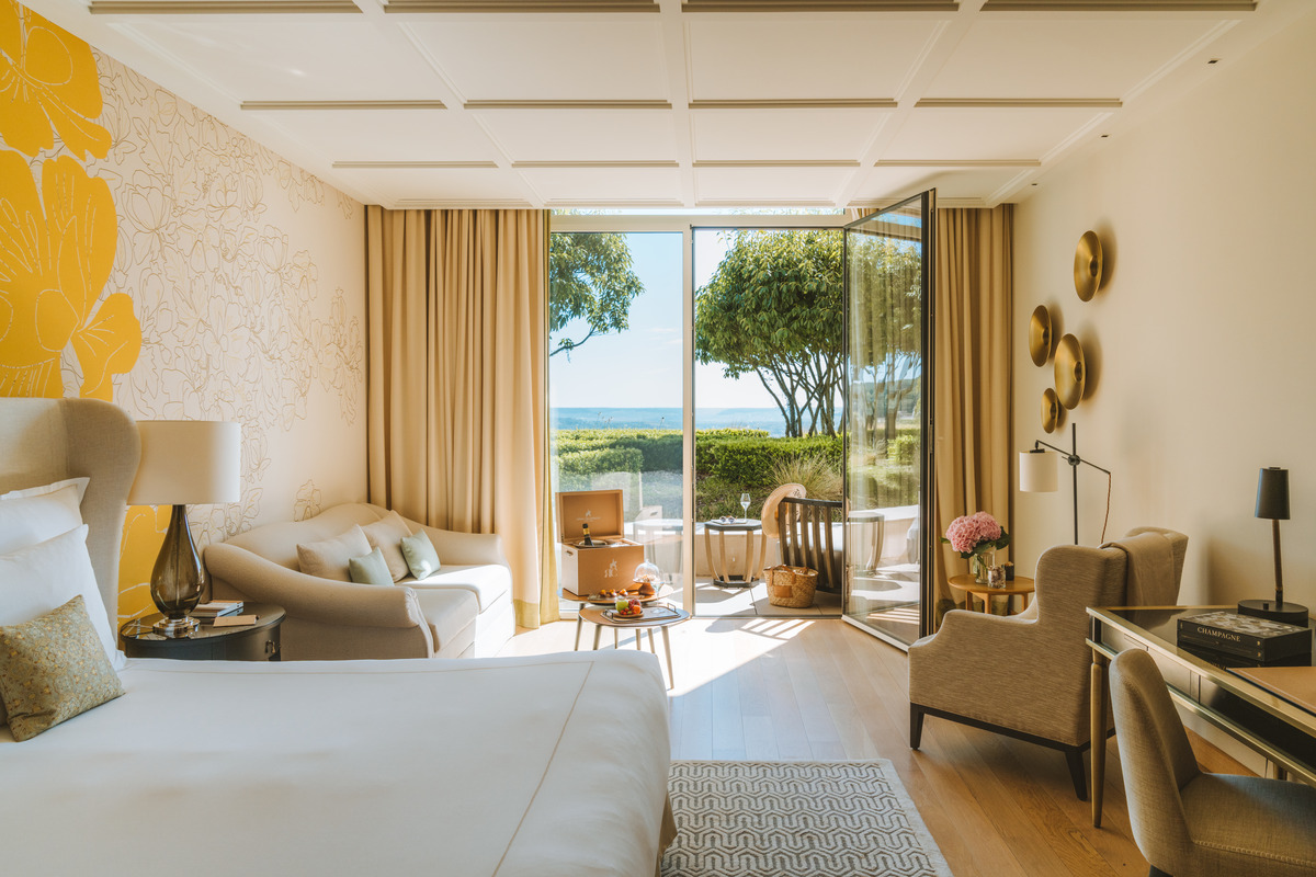 Champagne Junior Suite opening onto a terrace beside trees and a hedge, with the valley beyond.