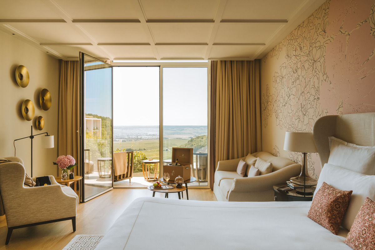Royal Junior Suite with a sofa, bed and open balcony overlooking the Champagne hills.