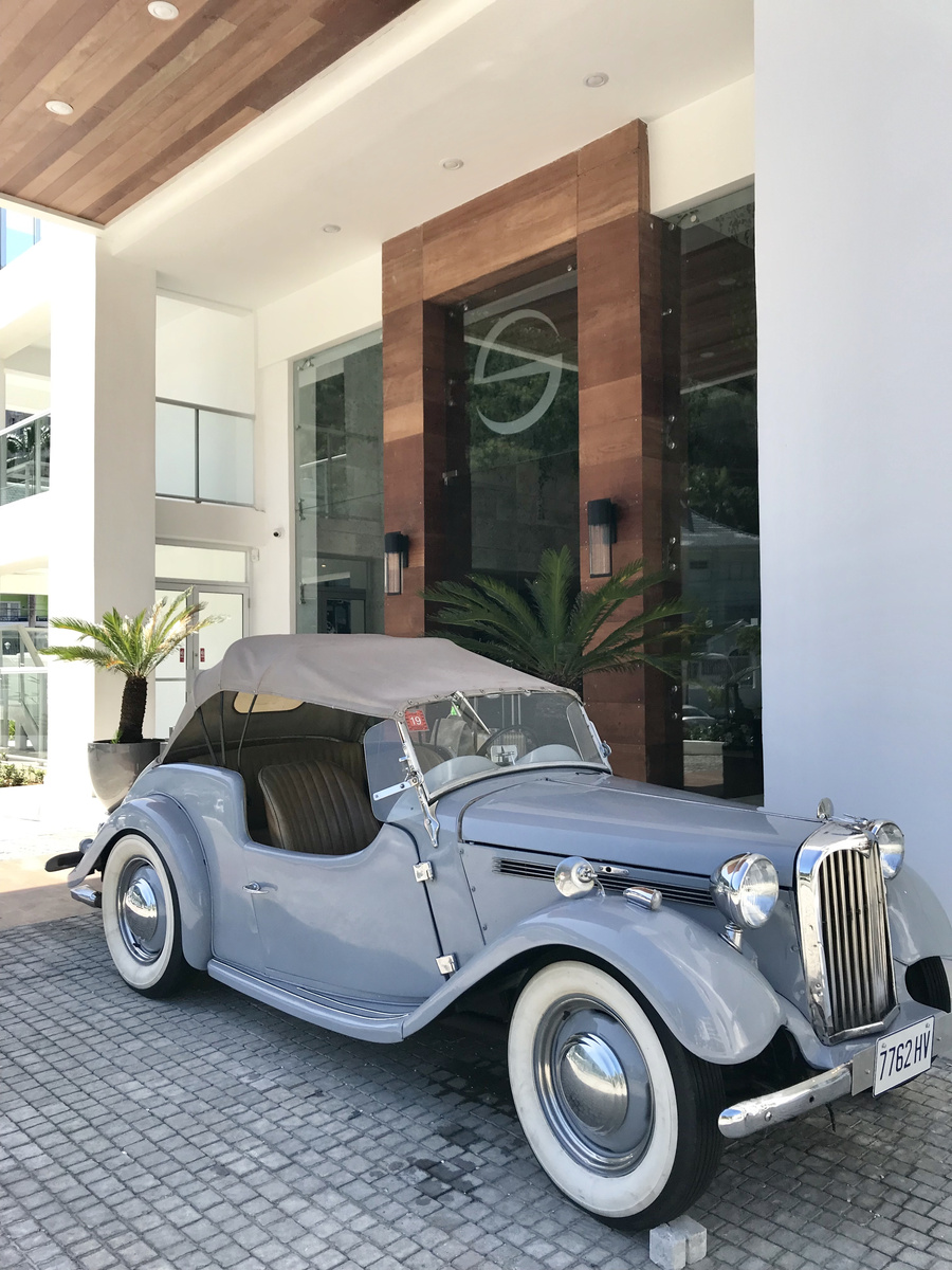 A pale blue vintage Singer parked beneath the entrance canopy of S Hotel Montego Bay.