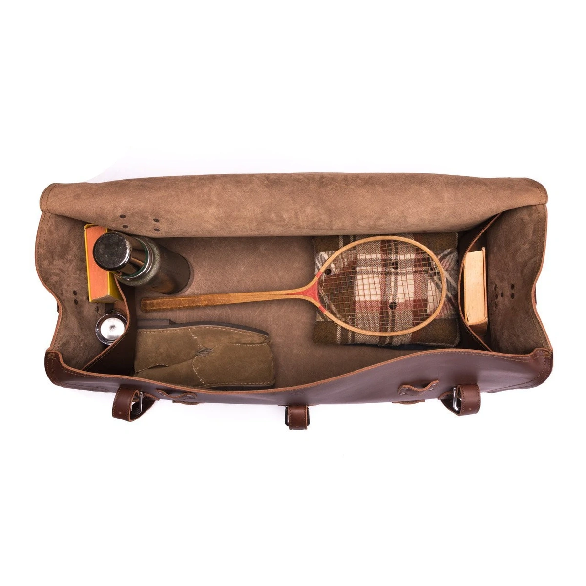 Open leather Beast duffle packed with a racket, blanket, flask and other travel belongings.