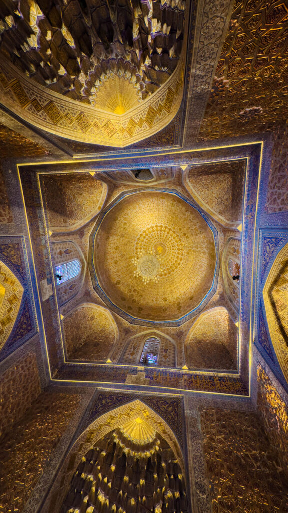 The blue and gold painted ceiling inside Tilya-Kori Madrasah, designed to appear as a deep dome.