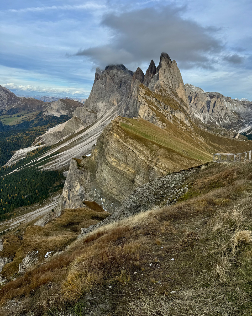 The jagged Seceda ridgeline above steep scree slopes and autumn meadows.