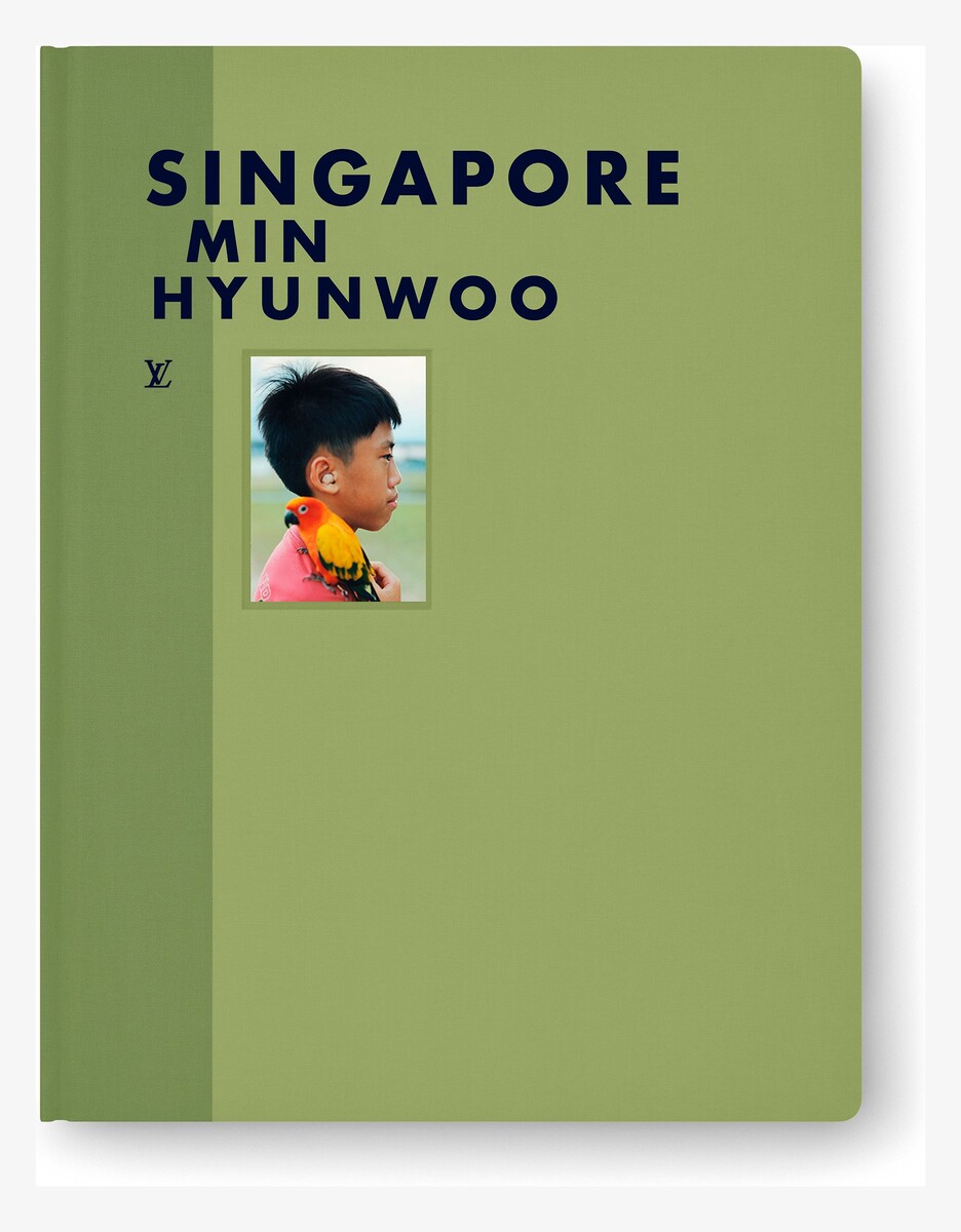 The green embossed cloth cover of Fashion Eye Singapore, with navy lettering and a photograph of a boy with a parrot.