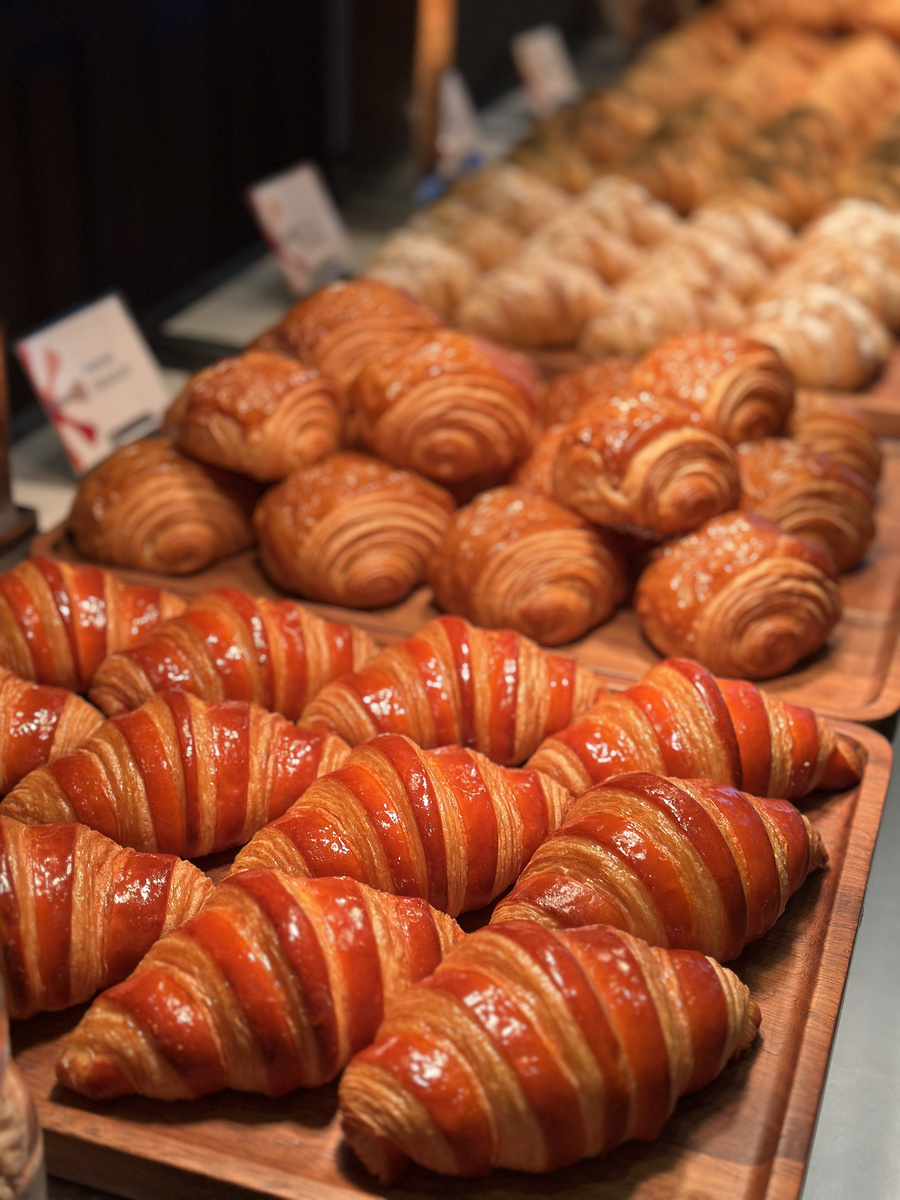 Rows of glazed croissants and other pastries at the breakfast buffet.
