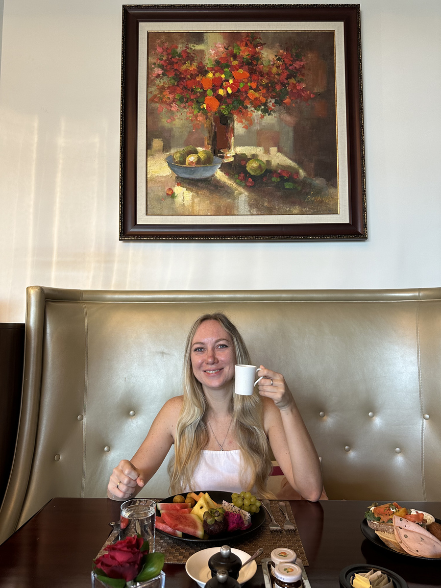 Olga smiling toward the camera with her coffee at The Terrace on the Corniche.