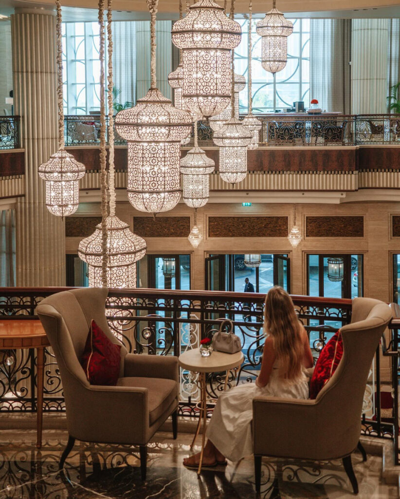 Olga seated on the upper lobby level beneath large suspended lanterns.