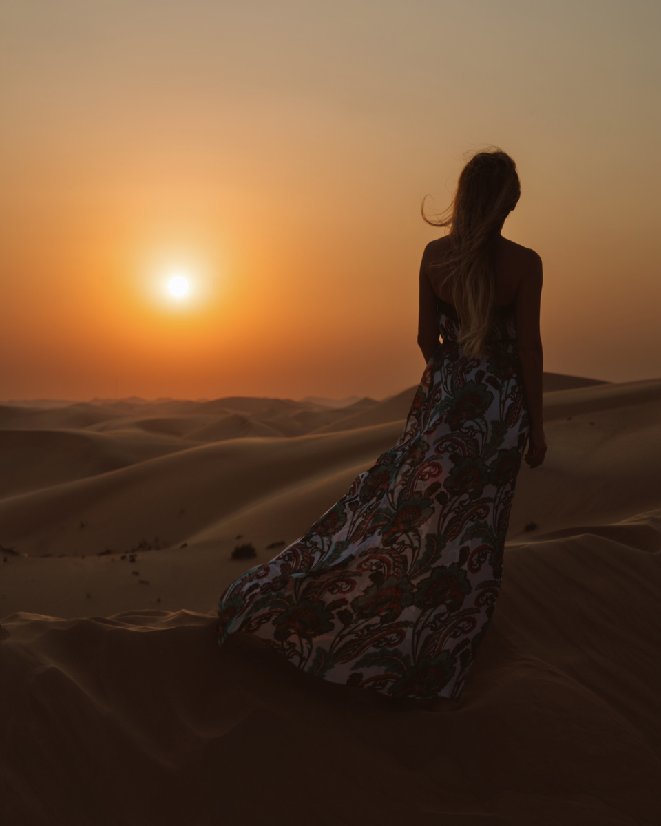 Olga standing on a dune as the sun sets over the desert near Abu Dhabi.