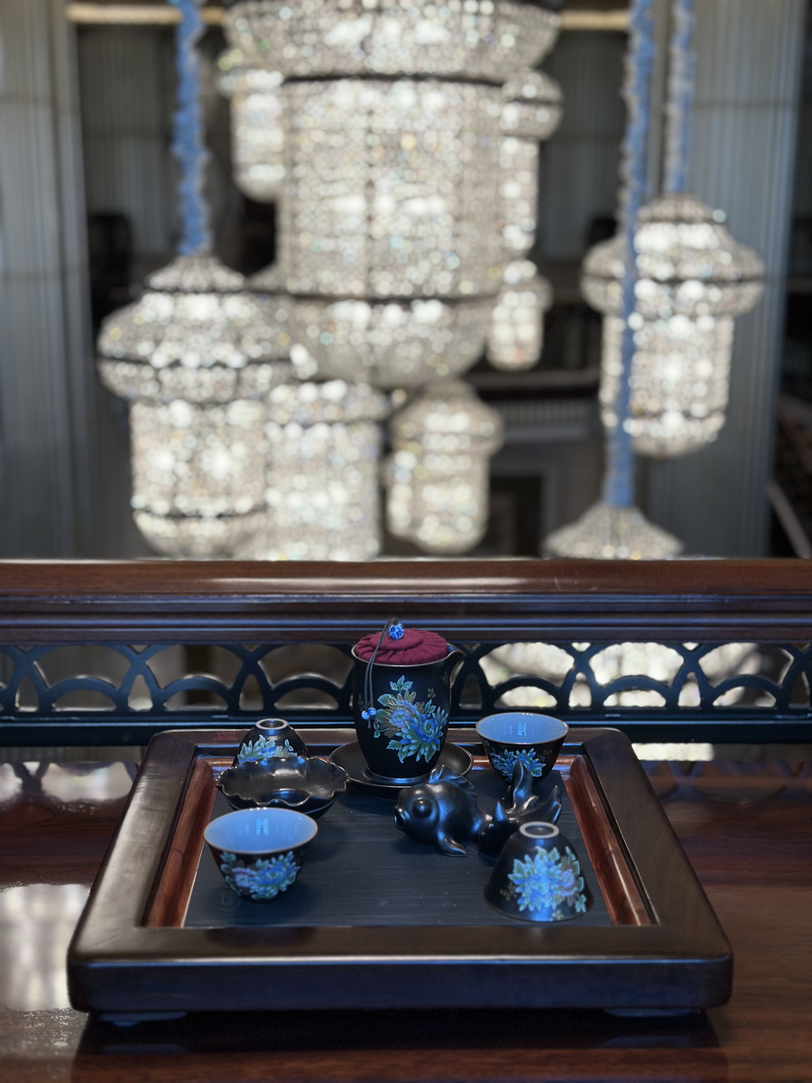 A tea service on a tray overlooking the hotel lobby and suspended lanterns.