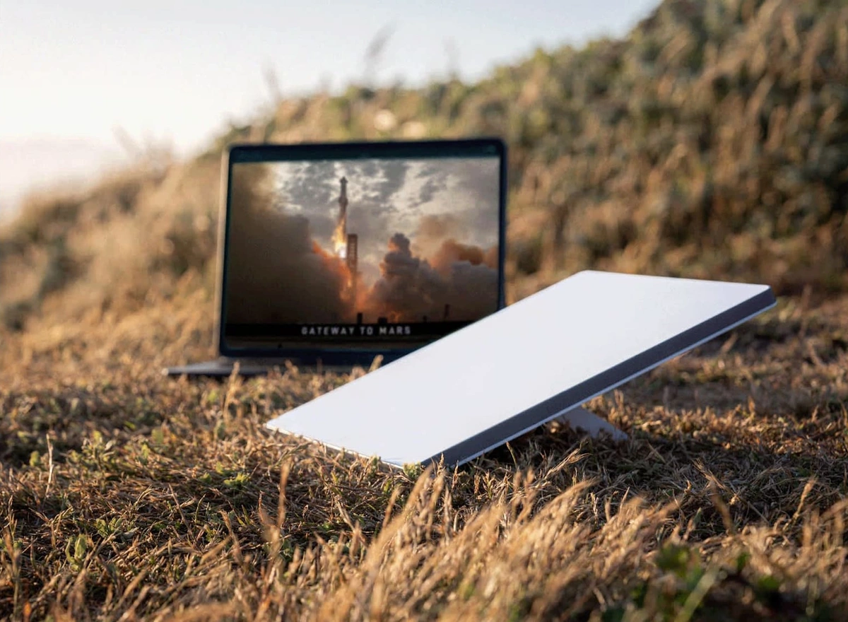 Starlink Mini on grass beside a screen showing a rocket launch.